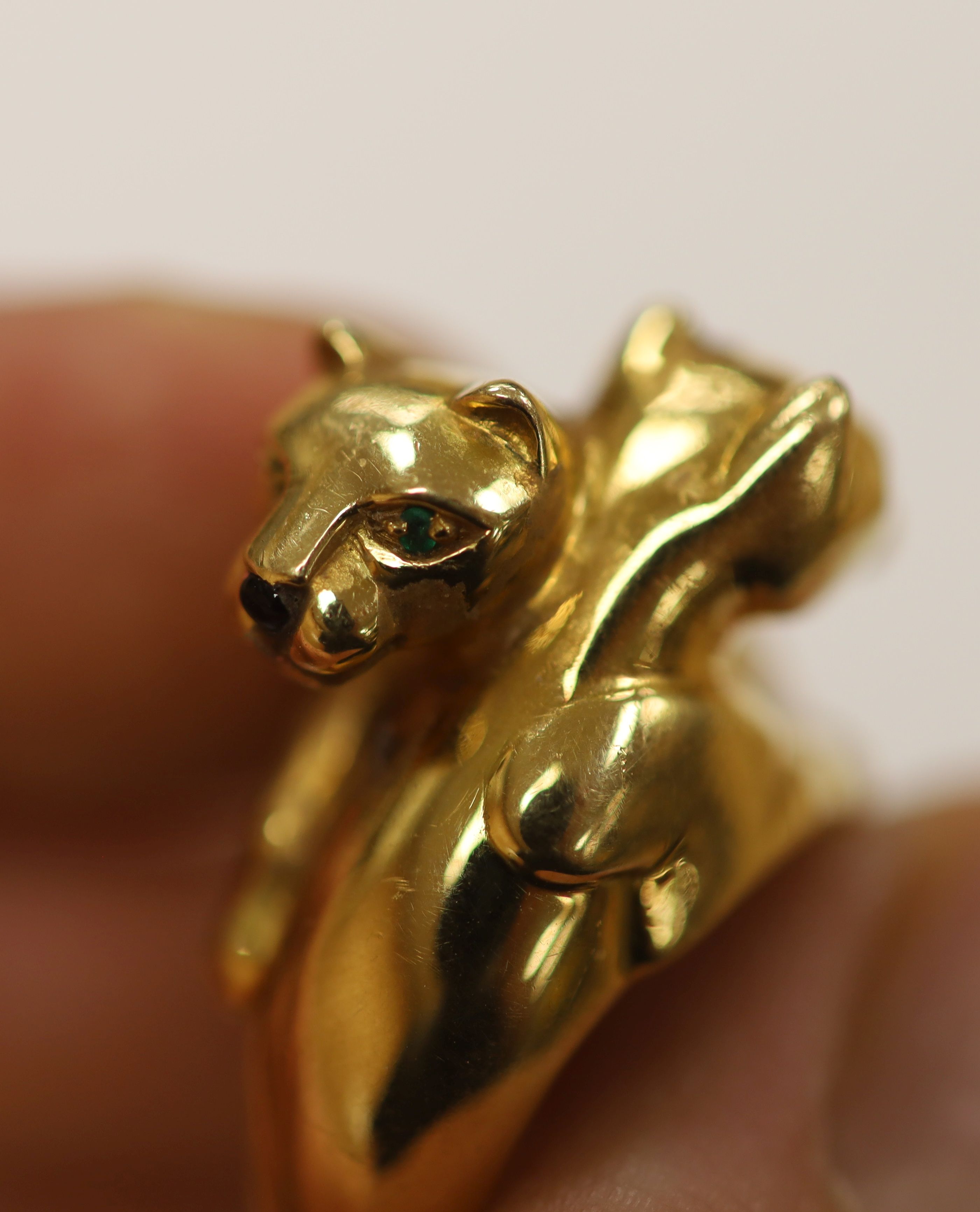 An early 1990's Cartier 18ct gold, black onyx and emerald set twin leopard's head crossover ring